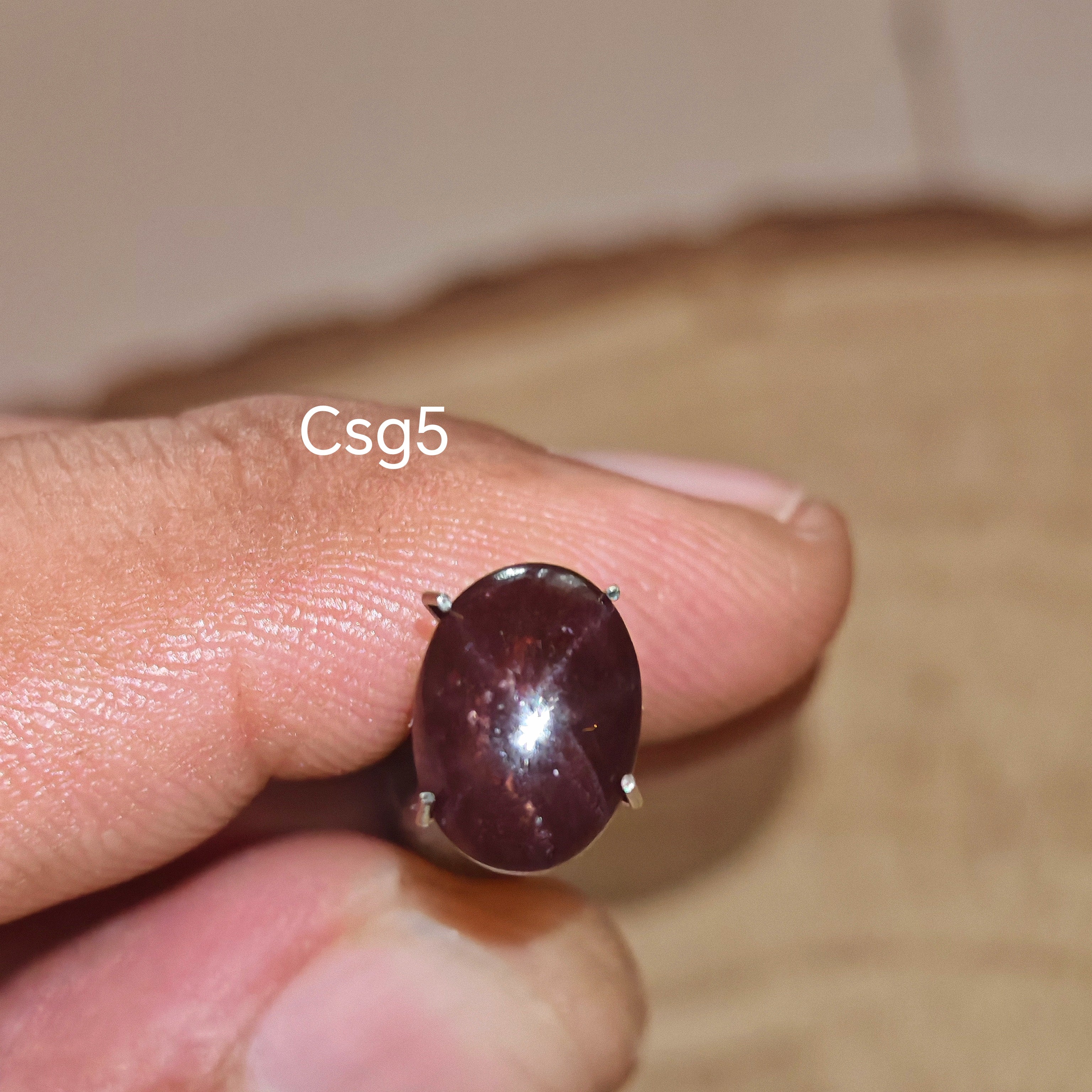 Star Garnet kabochon Csg5 – természetes csillag gránát kő kézben tartva, sötét bordó szín
