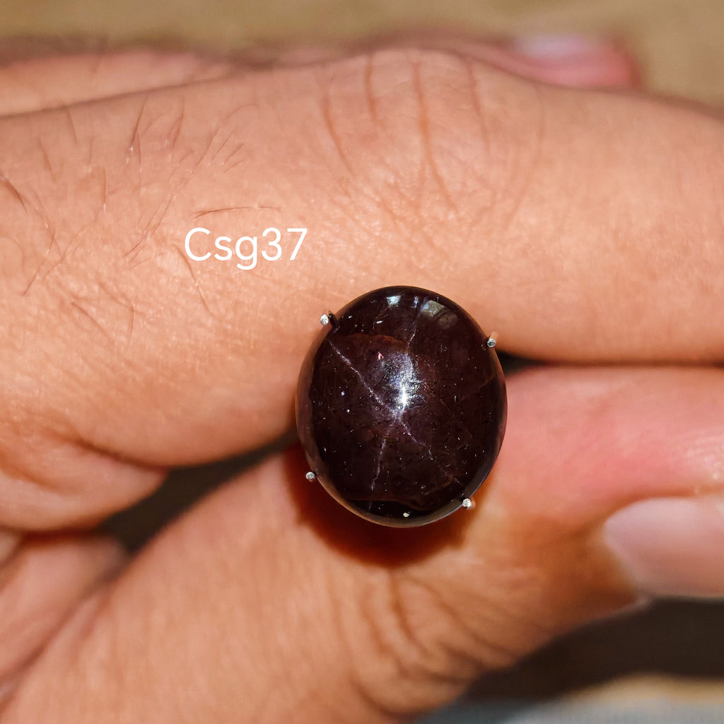 Star Garnet kabochon Csg37 – természetes csillag gránát kő kézben tartva, sötét bordó szín
