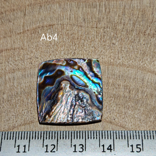 Abalone kagylóhéj kaboson, Ab4, ezüstös, kék és türkiz réteges irizáló mintázattal, milliméteres vonalzó mellett.