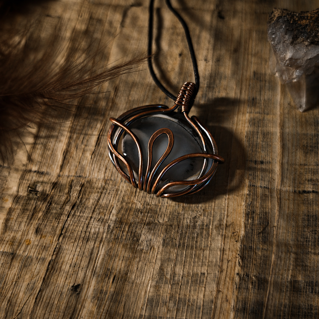 Lotus of Nefertem merlinit medál antikolt vörösréz lótusz drótfonásban, rusztikus fa felületen, kristály a háttérben – YourCrystal
