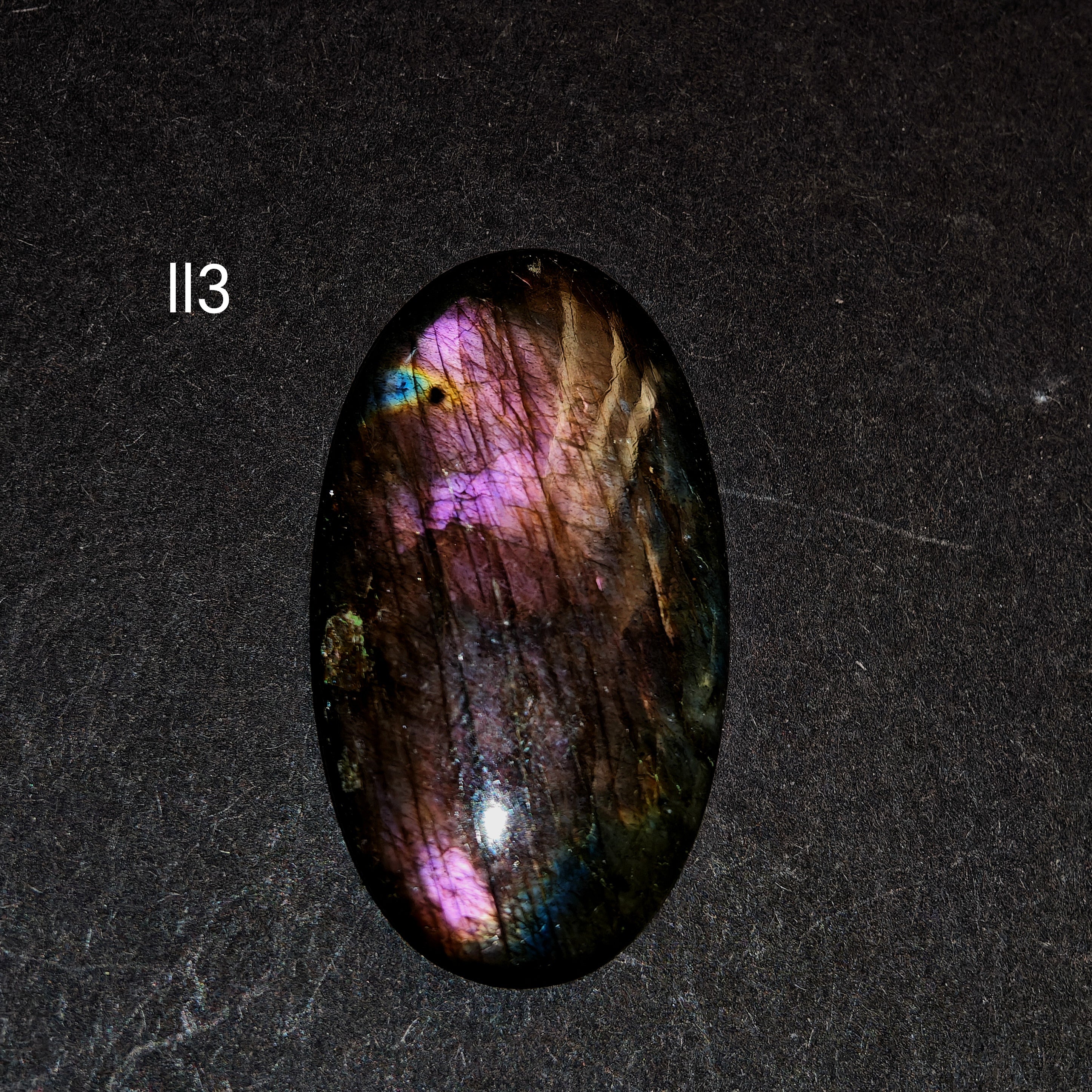 1. kép (fekete háttér, Ll3 felirat): Lila labradorit kabochon Ll3 – természetes ibolya flash spektrolit drágakő fekete háttéren


